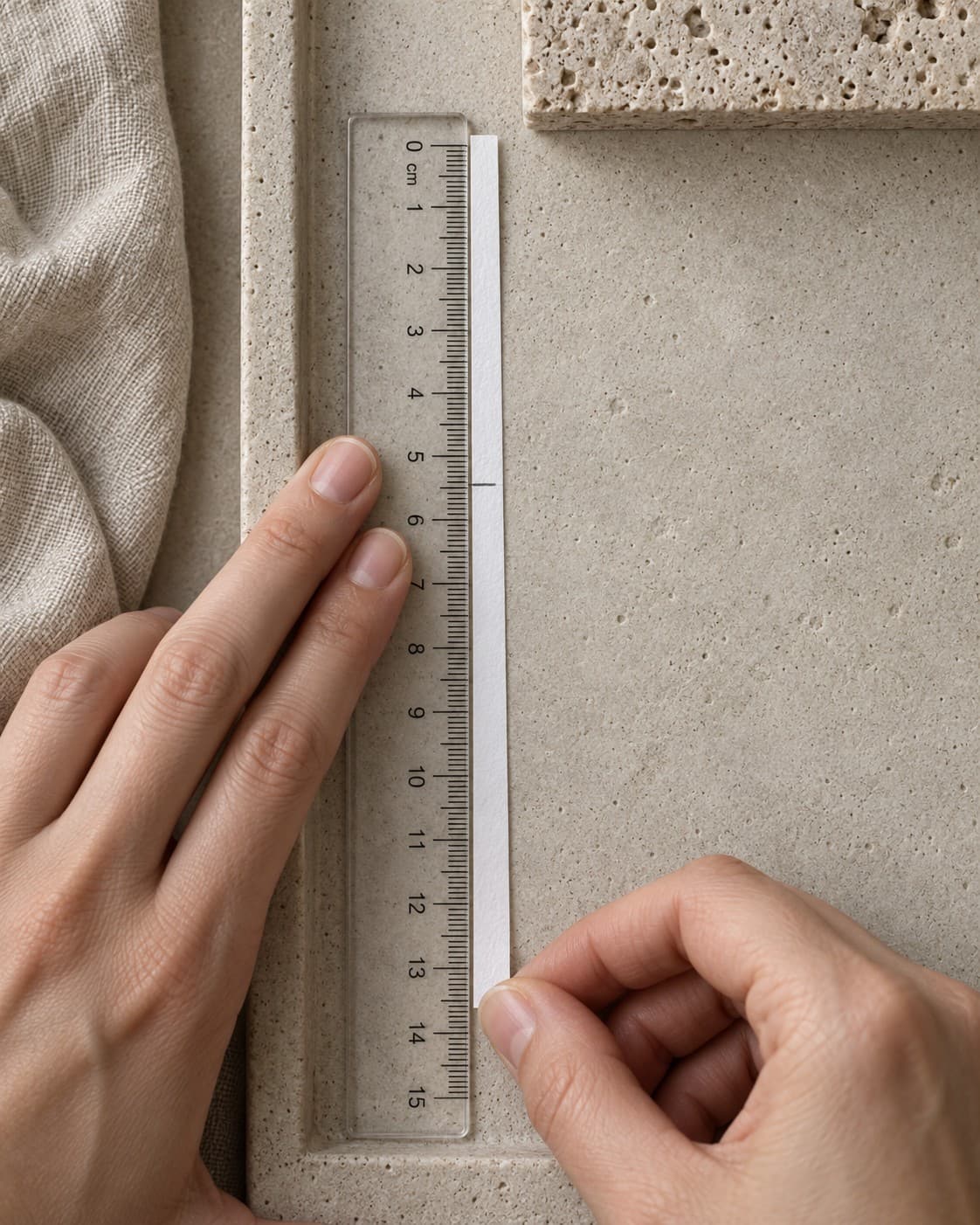 Tira de papel esticada ao lado de uma régua transparente, com a marca de lápis perto dos 5,5 centímetros.
